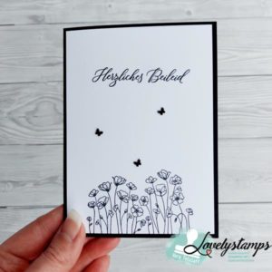 in der Hand gehaltene Trauerkarte mit Mohnblumen in schwarz und schwarzen Schmetterlingen