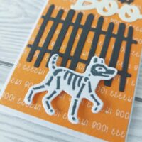 Geschenkumschlag in Kürbisgelb mit Zaun, einem Skeletthund und dem Wort BOO